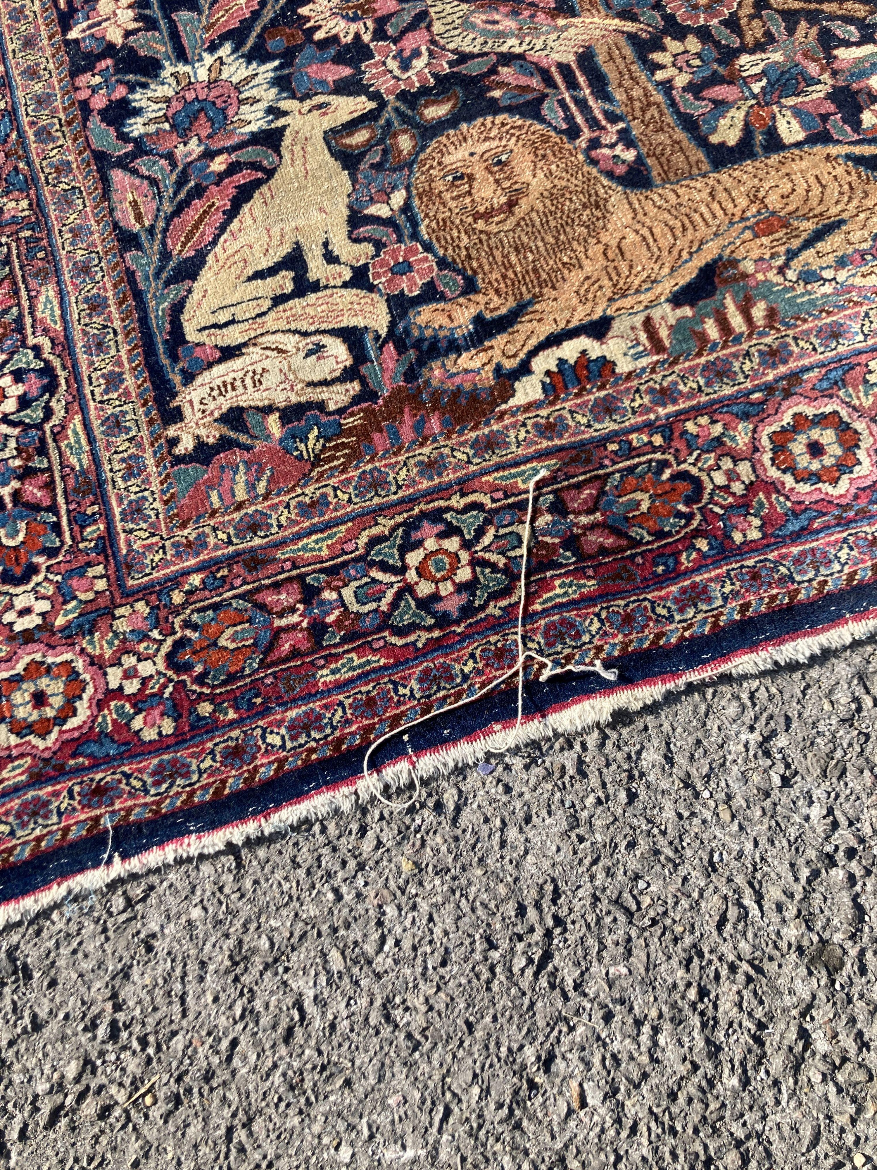 A Persian rug with a central Tree of Life interspersed with animals to include a seated monkey within the tree, a recumbent lion at the base, set within floral borders, 201 x 120cm